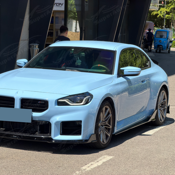 Gloss black SuperAutoUSA VTEN side skirts providing low-slung contrast on a Zandvoort Blue BMW M2