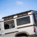 An overland-ready 2026 INEOS Grenadier with a rooftop tent secured to the cross bar carrier system.