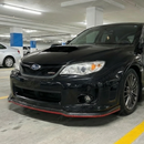Low angle shot showing the aggressive ground clearance and red trim of the STI front lip