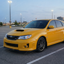 Low angle view showing the aggressive ground clearance of the STI gloss black splitter