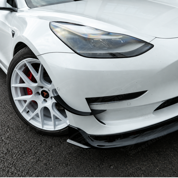 High-gloss black SuperAutoUSA VTEN 1-piece front lip creating a sharp contrast on a Pearl White Multi-Coat Tesla Model 3