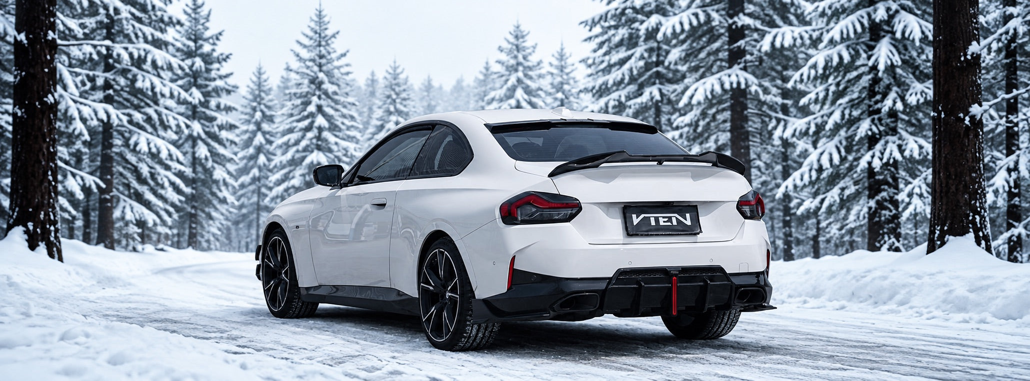 White BMW 2 Series fitted with VTEN aero on a snow-covered forest road